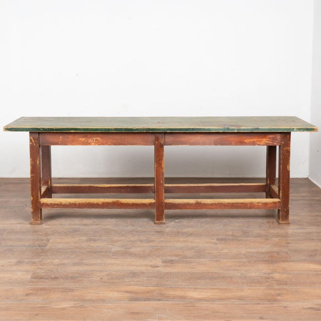 This 8' long rustic work table has a stretcher base with six legs. The base maintains it's original brown paint, while the...