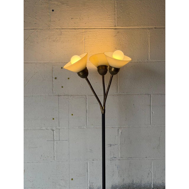 This striking floor lamp features a slender black metal stem and three adjustable gooseneck arms. The conical shades cast...