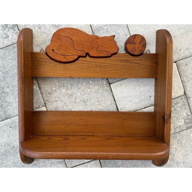 Vintage hand crafted wooden wall shelf featuring a decorative cutout of a sleeping cat and a ball of yarn along the top...