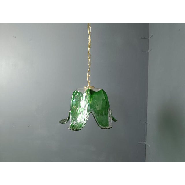 Vintage murano glass green pendant light with a brass shade holder and chain. Beautiful hand made glass dome emitting a...