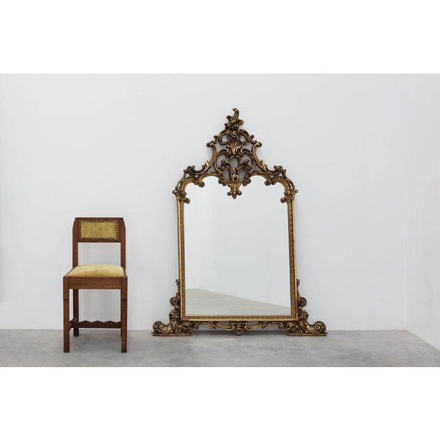 An impressive Belgian mirror in the Rococo style, featuring a richly carved resin frame with a gilt finish. The design is...