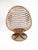 This vintage rattan lounge chair features a dramatic high-backed, egg-shaped silhouette with an open woven construction....