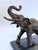 This bronze sculpture captures the majesty of a bull elephant in mid-stride, its trunk raised high in a classic gesture of...