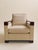 This armchair pairs a tailored beige upholstered body with sculptural walnut arms and a matching walnut base, creating a...