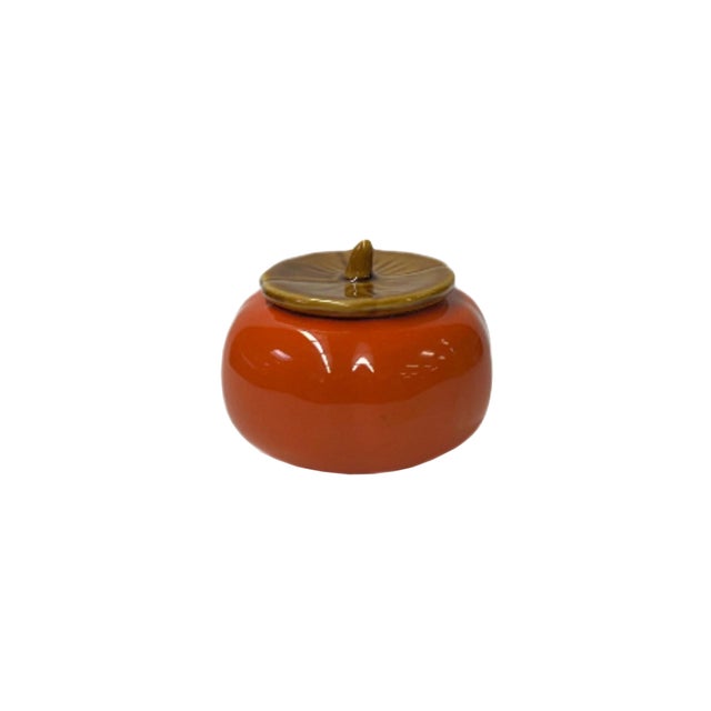 This charming ceramic jar is delightfully designed to resemble a ripe persimmon, exuding a playful yet elegant aesthetic....
