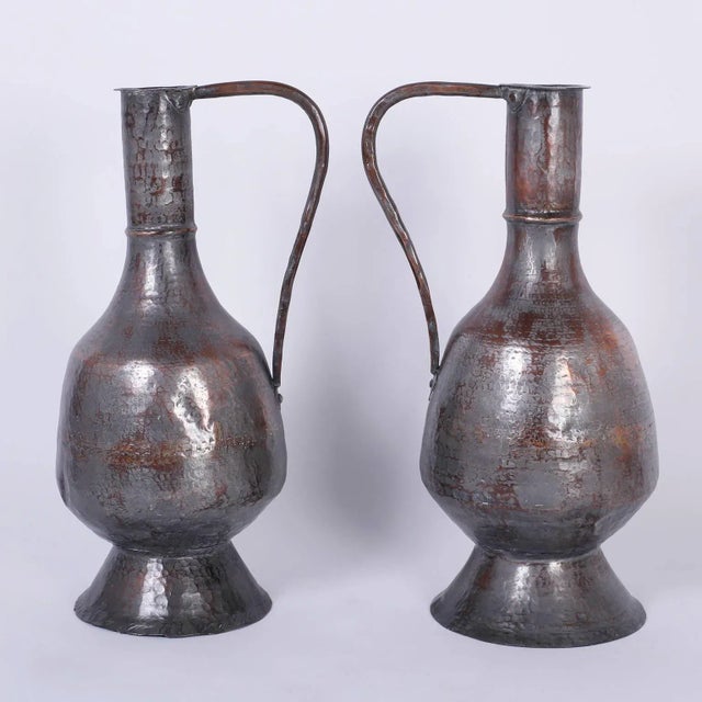 Antique pair of water pitchers or jugs handcrafted with copper, hammered, riveted, and plated with a translucent silver...