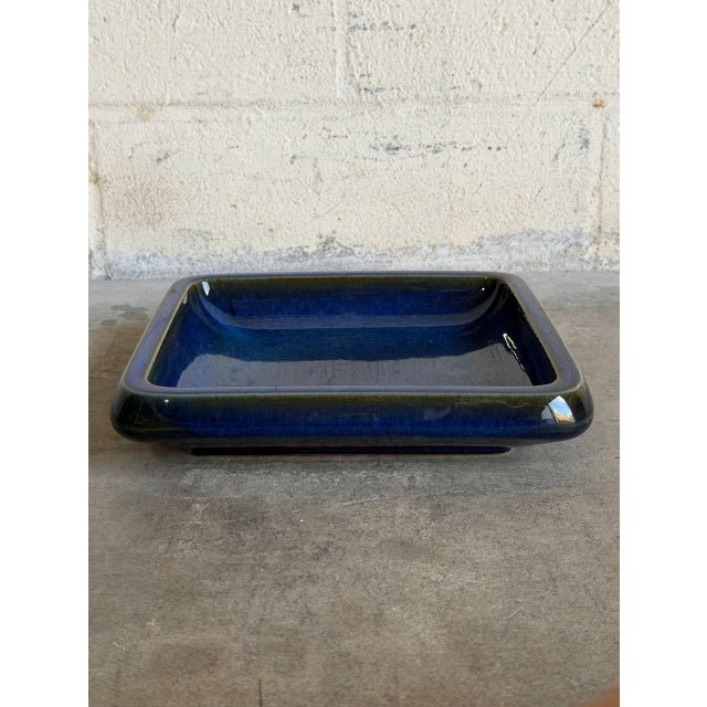 This vintage ceramic serving dish features a clean square form with a gently recessed center and raised edges. The...
