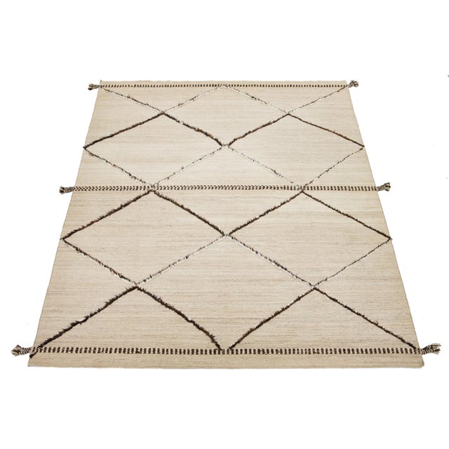 This handcrafted, contemporary Moroccan-style wool rug features a stunning beige and light brown background that...
