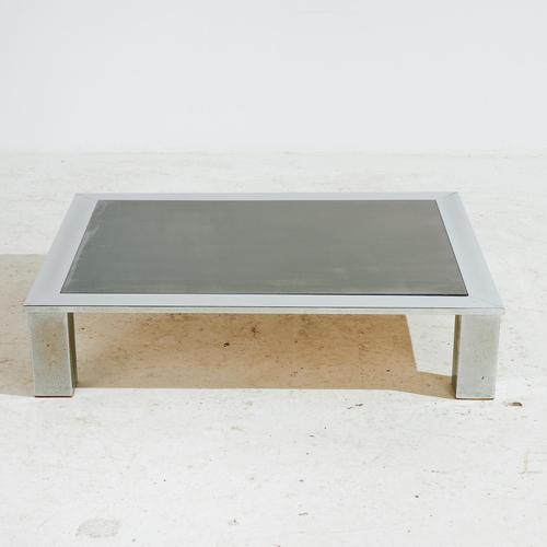 Angular shaped coffee table with chrome legs and smoked glass top from the 1970s. with some surface scratches and wear on...