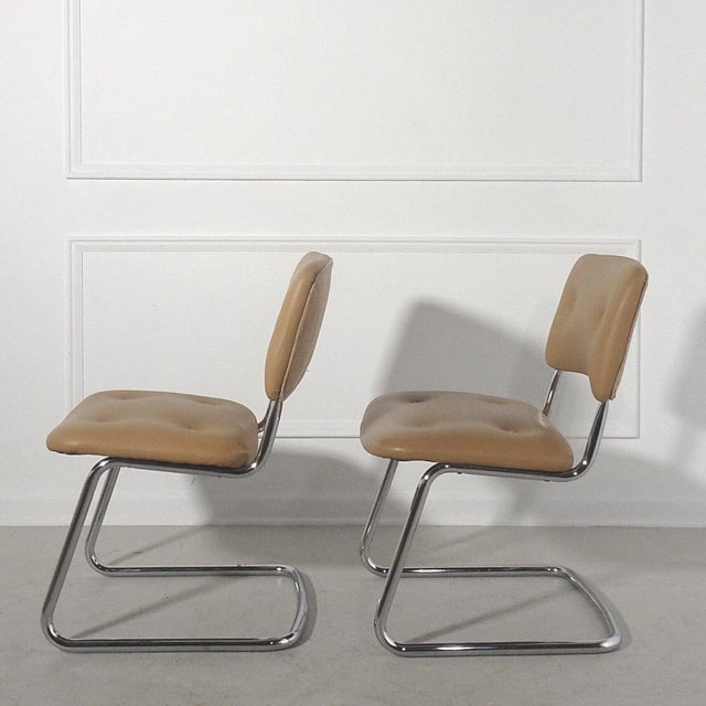 Vintage modern cantilever tubular chrome side chairs upholstered in a camel faux leather with a complimentary camel...