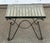 This small wrought iron table rests on a folding-style X-frame of looped and scrolled rods. A slatted iron top with a...