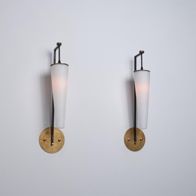 Pair of italian wall sconces dating from the 1950s, characterized by a slender geometric structure and a refined...