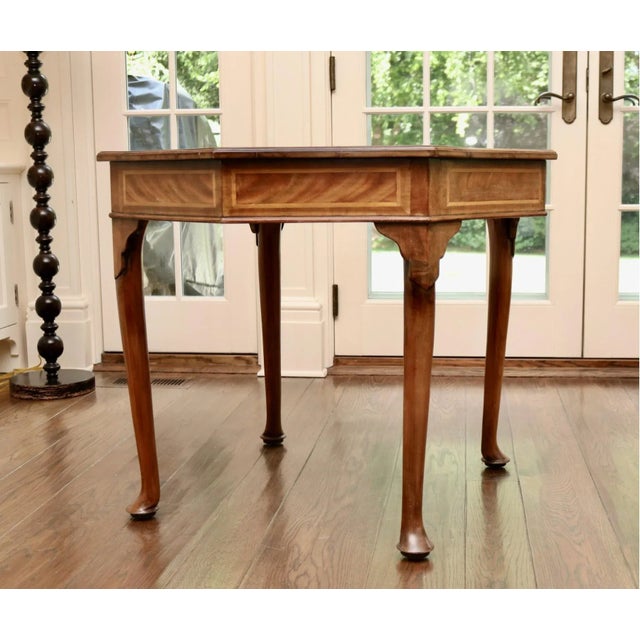 A classically styled George III octagonal mahogany game table with a gilt and blind-stamped brown leather top, satinwood...