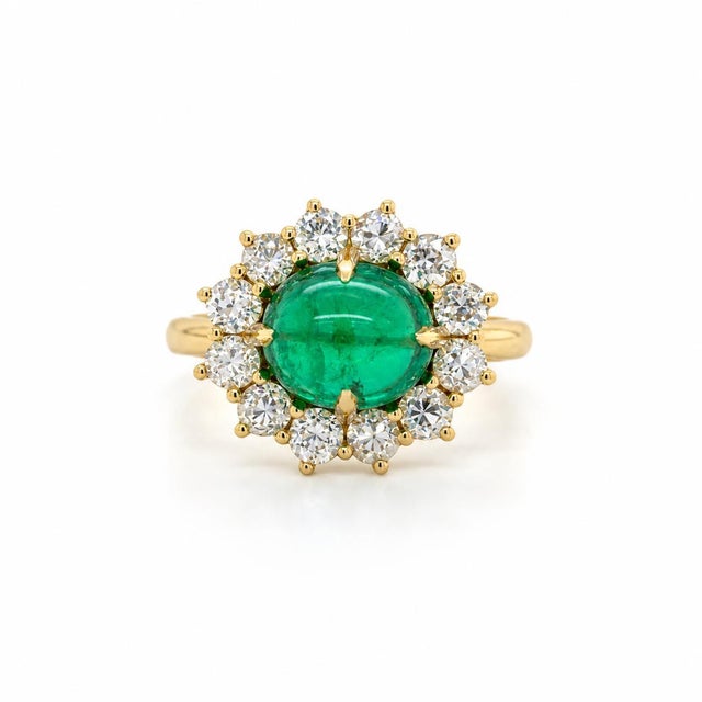 A captivating 18-karat yellow gold ring centered by a superb 3.32-carat Colombian cabochon-cut emerald, exhibiting a rich,...