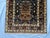 A hand-knotted Afghan tribal rug on a deep indigo field, carrying three large handled urns down the length of the rug in...