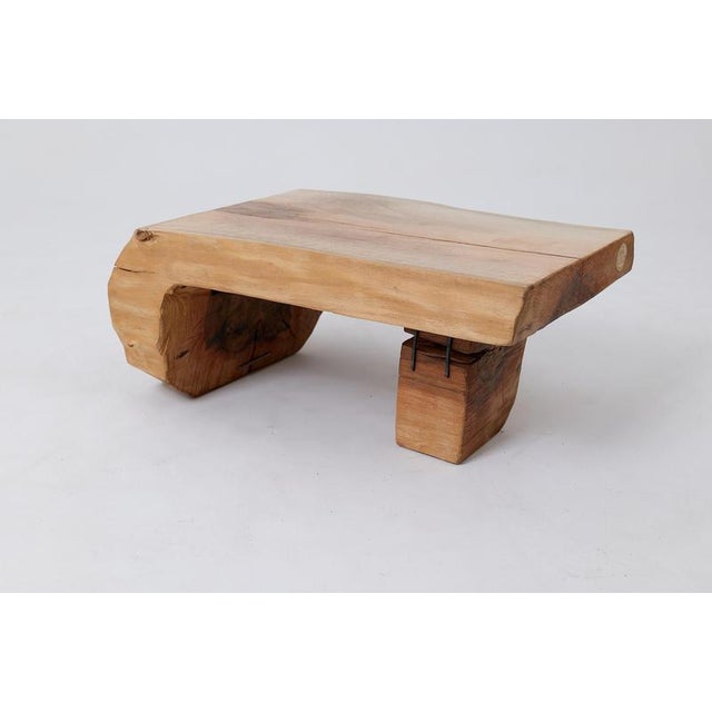 This unique low table or bench is carved from a single piece of wood, showcasing a monolithic form that feels grounded and...