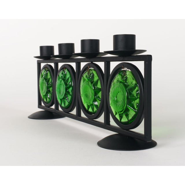 A vintage four-arm candelabrum of black-lacquered steel and four discs / suncatchers of green cast glass depicting...