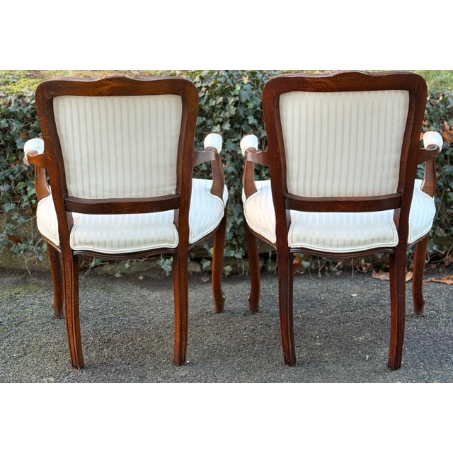 Beautiful matching pair of Louis XV-style fauteuil armchairs with dark wood frames. The chairs feature elegant carved...