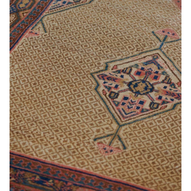 This antique, circa 1900, Serab rug has a sandy-yellow field with an overall caramel-brown linked lozenge lattice each...