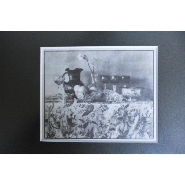 A small hand coated, hand processed palladium print still life showing a pitcher, wine glasses, a basket of eggs, and a...