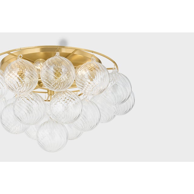Swirl-ribbed or plated champagne glass globes dangle from an Aged Brass frame, creating this cloud-like showstopper....