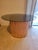 Vintage but modern round table featuring an expresso decorative glass top resting over a sculptural cylindrical slatted...