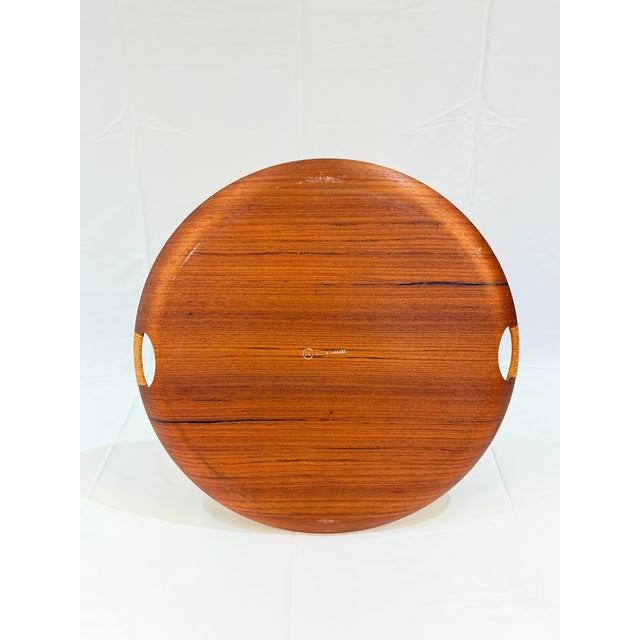 A generously scaled round teak serving tray with the clean lines and warm material character associated with Danish modern...