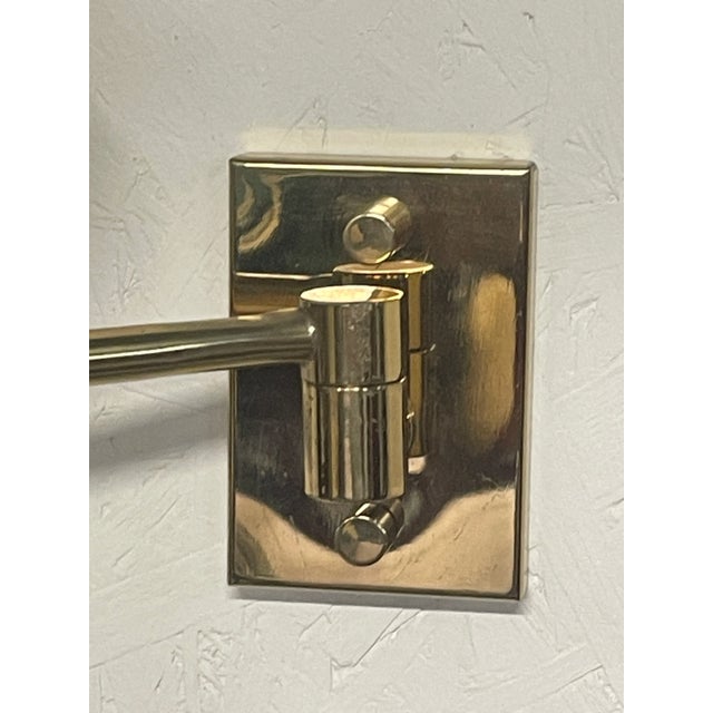 A pair of 1970s brass wall lamps with a timeless design. The wall lamps have a movable arm and are ideal as supplemental...