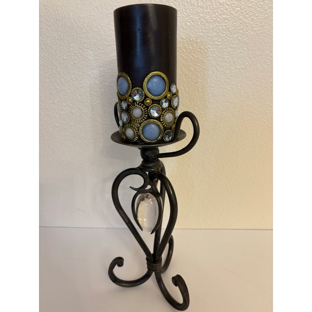 A pair of two wrought iron candle holders featuring clear glass heart-shaped teardrop inserts suspended in the center....