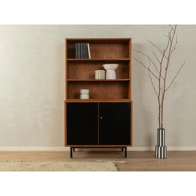Classic chest of drawers from the 1960s. Body in teak veneer with two Formica-coated doors in black, three shelves and new...
