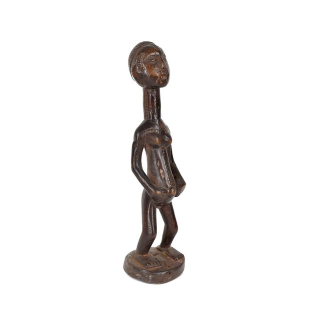 Female figure with scarification patterns on face and torso. A hole at the top of the head probably once housed a horn....
