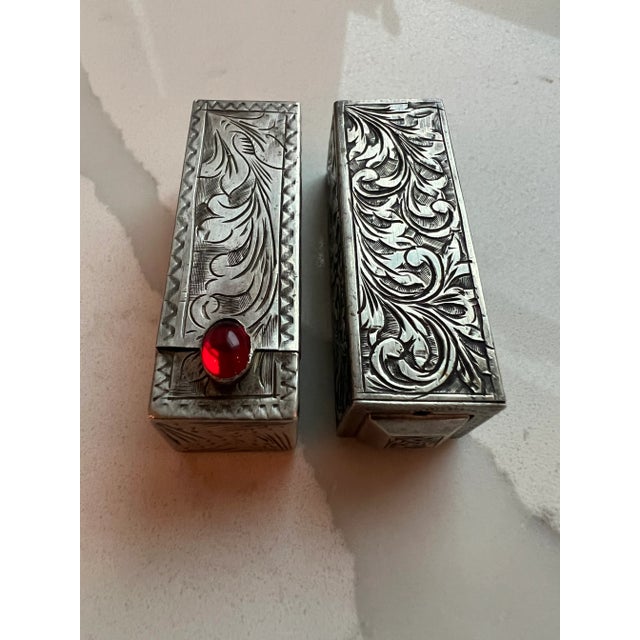 Collection includes: Two silver lipstick cases with spring open mirrors. Three glass perfume bottles with silver lids and...