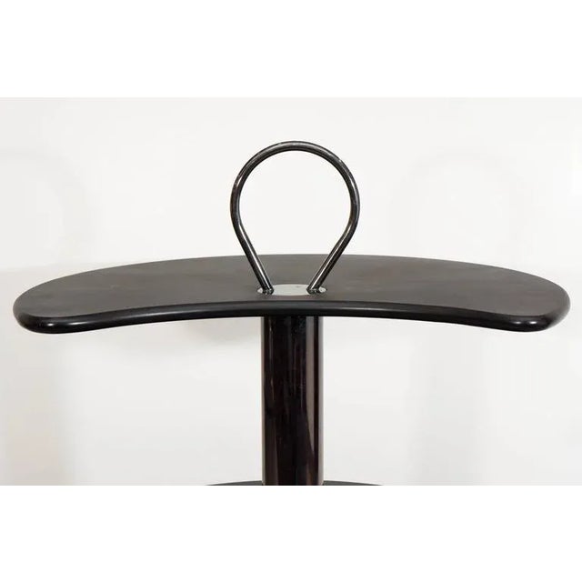 This circular bar cart by Design Institute of America (DIA) comes in black lacquered wood with three tiers of revolving...