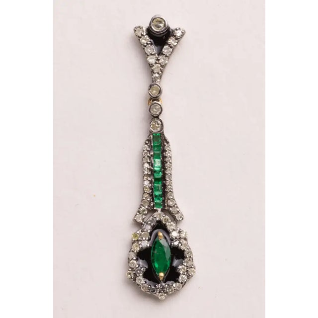 A pair of lovely emerald and diamond dangle drop earrings. The emeralds feature a line of channel set emeralds and a...