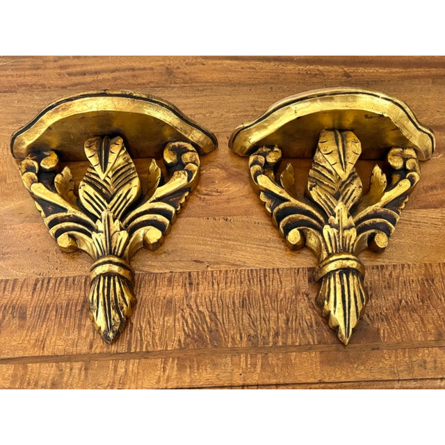 A pair of carved gilt-wood wall brackets or shelves based on the Prince of Wales Feather design. Made in Italy in the mid...