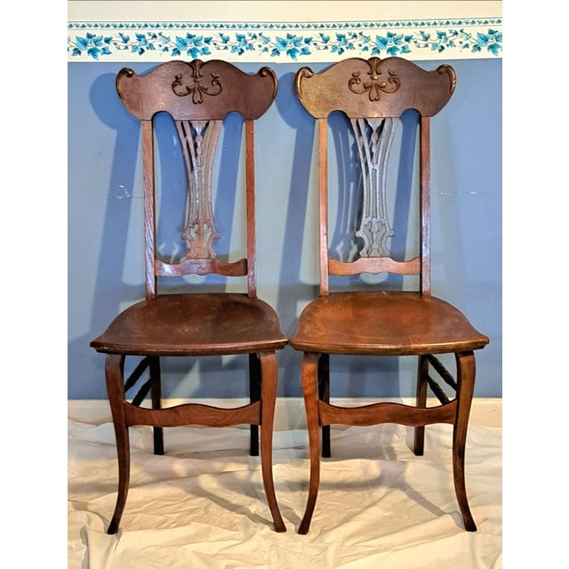 This elegant pair of antique chairs, dating to the early 20th century (circa 1900), is crafted from solid quarter-sawn oak...