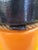 A bold and authentic mid-century commercial fishing buoy, painted in signal orange and black with its original rope seam...