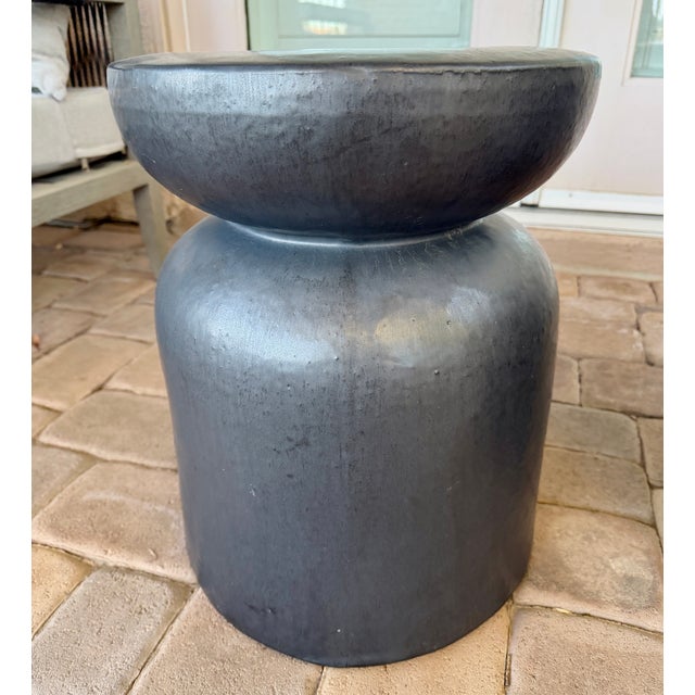 This set of two outdoor side tables and attributed to Made Goods features a bold, sculptural silhouette with a refined...