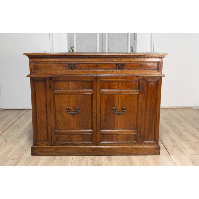 An Italian walnut buffet from the 17th century with drop front section, hidden drawers, two doors and carved dentil...