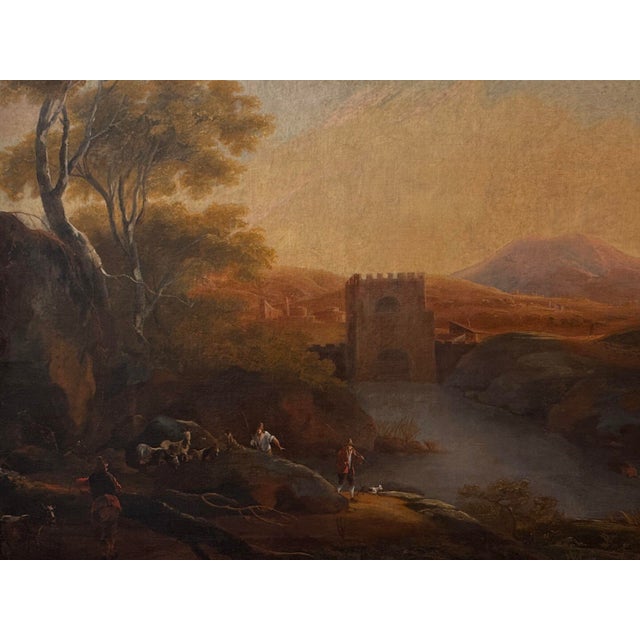 An 18th C. Italian landscape painting of herdsmen, goats and a small dog on a rocky path beside a river. Beyond them a...