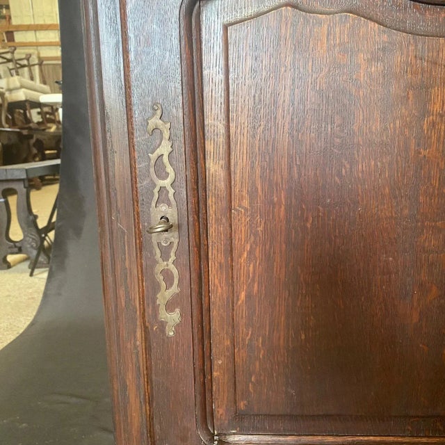 A French Louis XV period solid oak buffet having a pair of carved doors that hang on steel barrel hinges with hand cut...