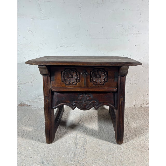 Charming small Spanish side table crafted in solid wood, featuring a carved drawer front with floral motifs and original...