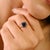 This elegant solitaire ring features a 1.33 carat Asscher-cut blue sapphire set in a sleek 18K yellow gold band, featuring...