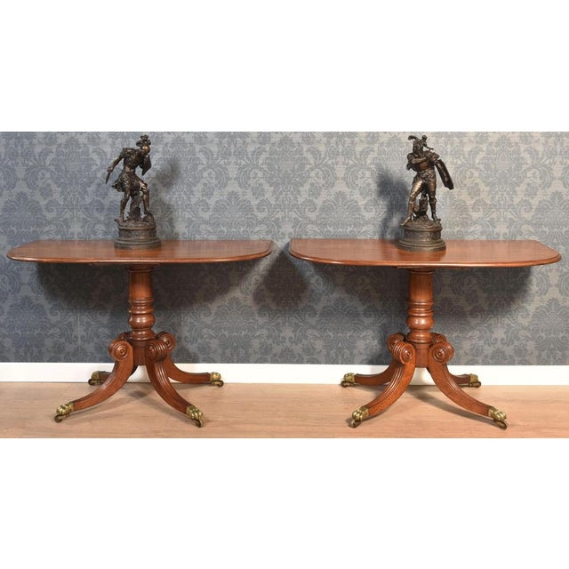 Pair of Regency hall tables, the well figured mahogany tops supported on turned columns. All raised up on four saber legs,...