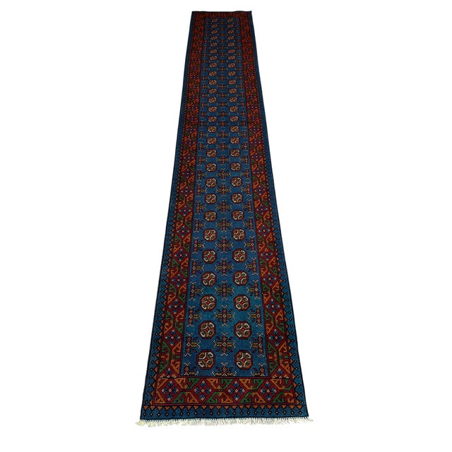 This extra-long tribal wool runner features two rows of repeating geometric medallions across a deep teal-blue field....