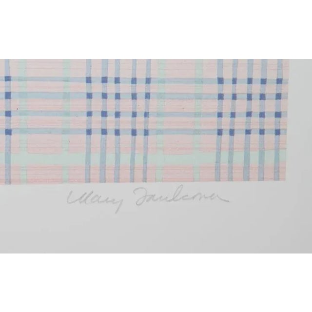 Resting on a blue-and-pink checkered tablecloth against a soft pink wall, the white handled jar at center overflows with...