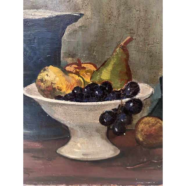 A vintage oil painting on Masonite depicting a young boy seated beside a still life arrangement of fruit and a dark...