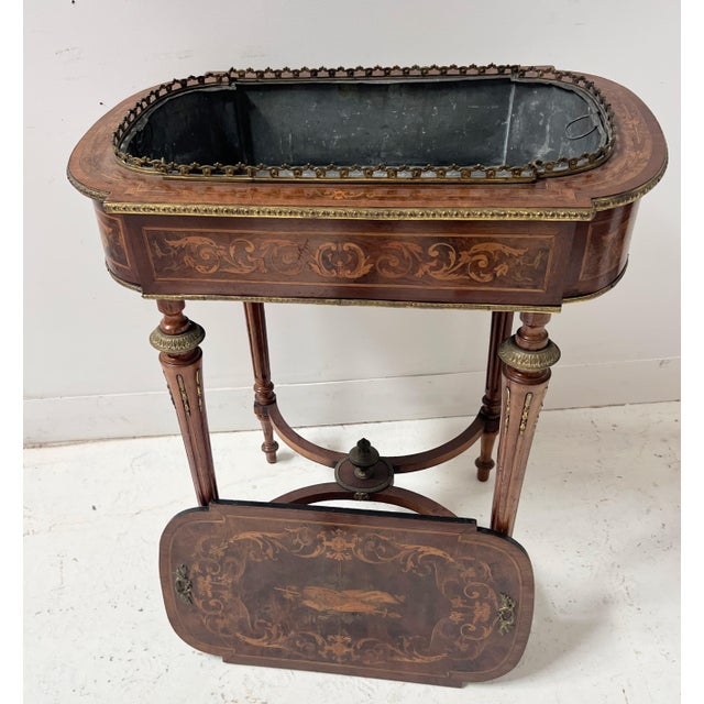 A napoleon iii marquetry jardinière in veneered wood. it rests on four tapered, fluted feet with brass rings. the...