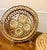 This is a circular, intricately woven decorative wall hanging adorned with numerous light-colored cowrie shells. Crafted...