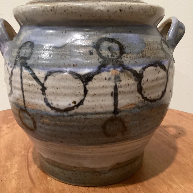 This vintage studio art pottery casserole dish/tureen is a round, multicolored stoneware piece signed by the studio...